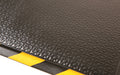Close up product image of edge of black nitrile rubber Happy Feet Texture Top Mat with safety border