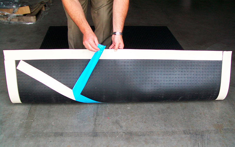 Insitu image of someone using double sided tape for easy installation of the Waterhog Truck Mat,