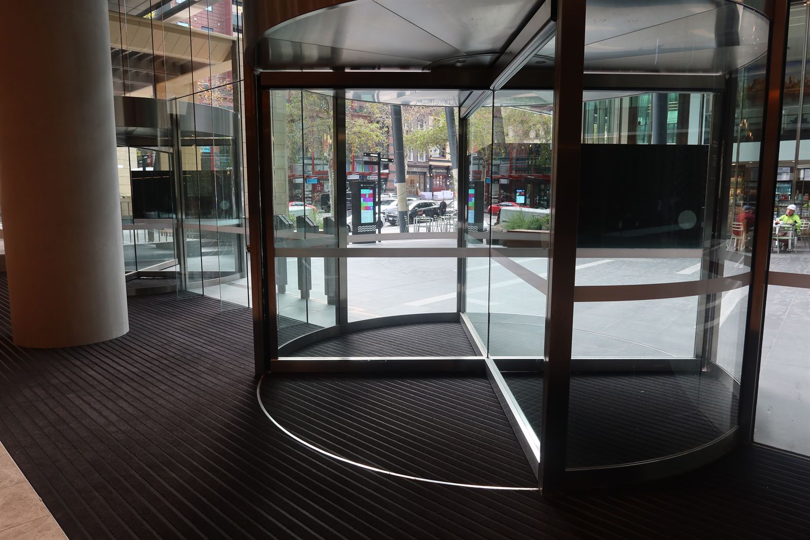 ARCHIMAT entrance matting installed around revolving doors at a commercial building entrance